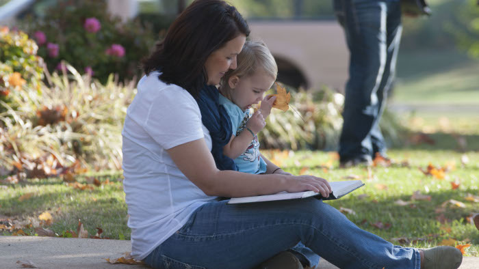 Adult reading to a child outside