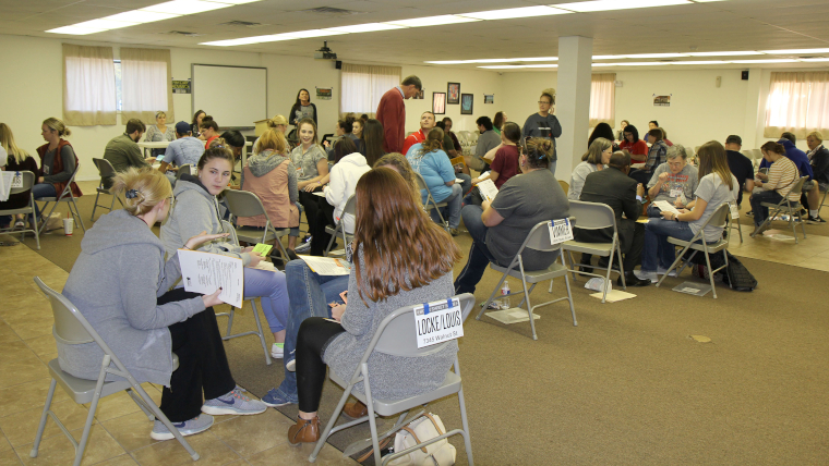 students in a large room sitting in chairs in breakout groups 