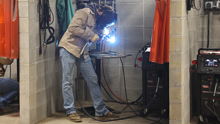 Welder working on his work in his welding booth.