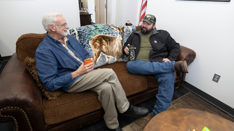two veteran guys talking on a couch