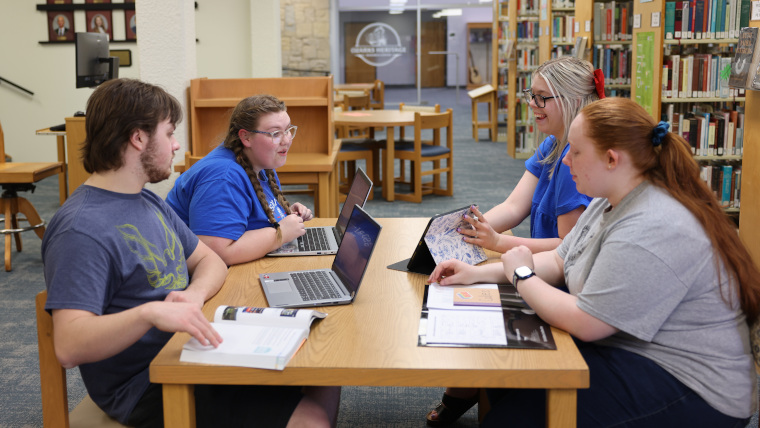 four students studying in the library
