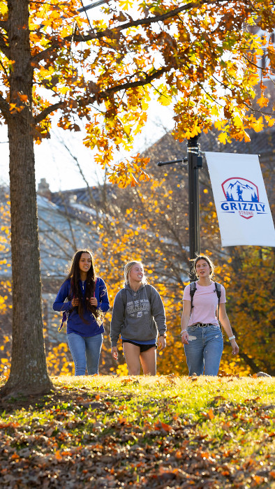 three students walking by library in the fall