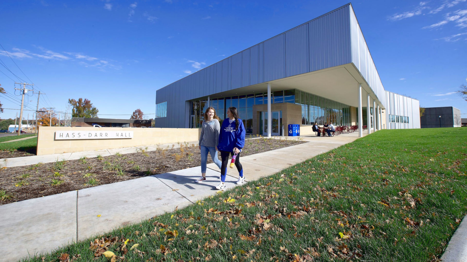 Two female students walking in front of Hass-Darr Hall in early Autumn