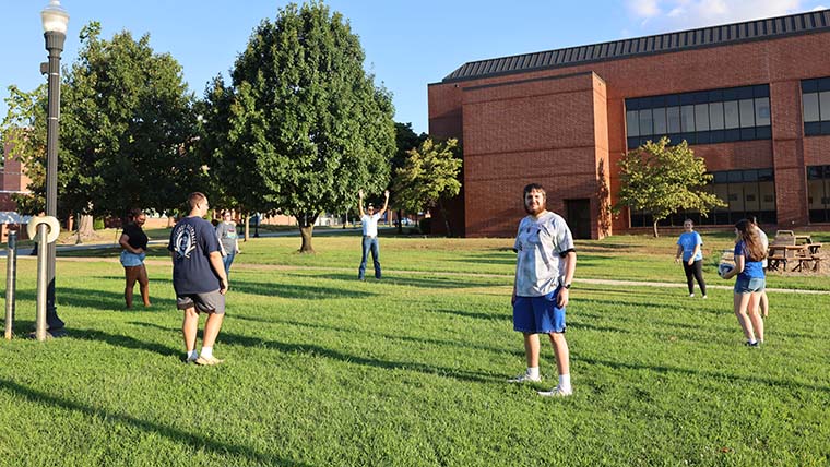 Group of students playing with a volleyball by Melton Hall