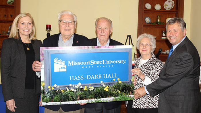 Members of the Hass and Darr families holding a concept photo of the sign for the new Hass-Darr Hall.