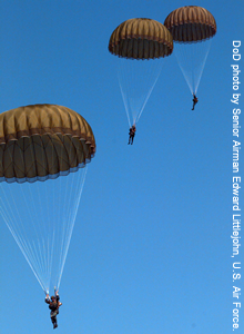 Military personnel in parachutes floating to the ground.
