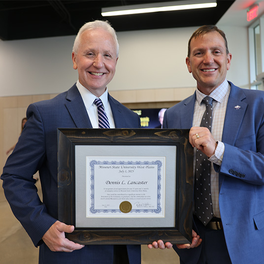 Chancellor Lancaster and President Williams at the Board of Governors reception. Williams is presenting Lancaster a certificate for retirement