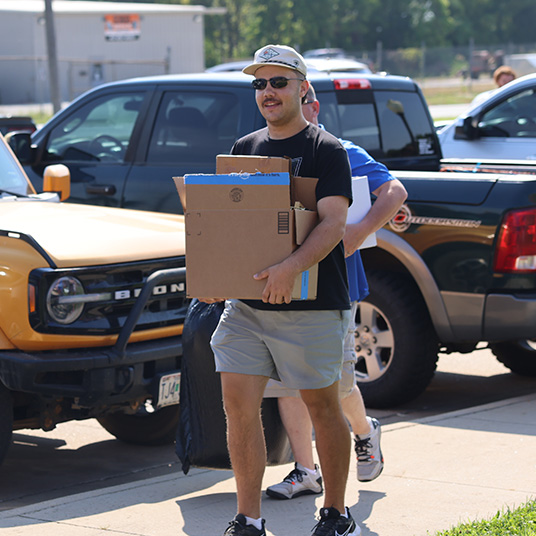 Student carries box on move-in weekend.