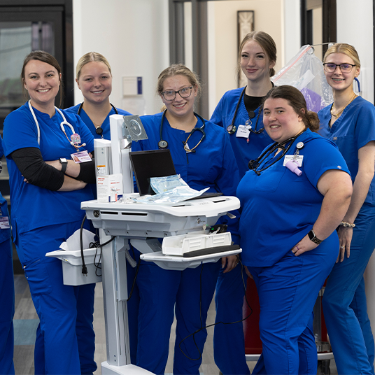 Nursing students pose for group photo wearing scrubs