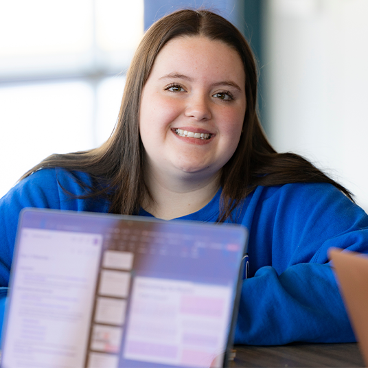 Student smiling with laptop in foreground