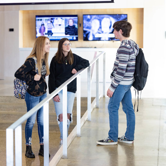 Three students engage in conversation in Hass-Darr Hall 