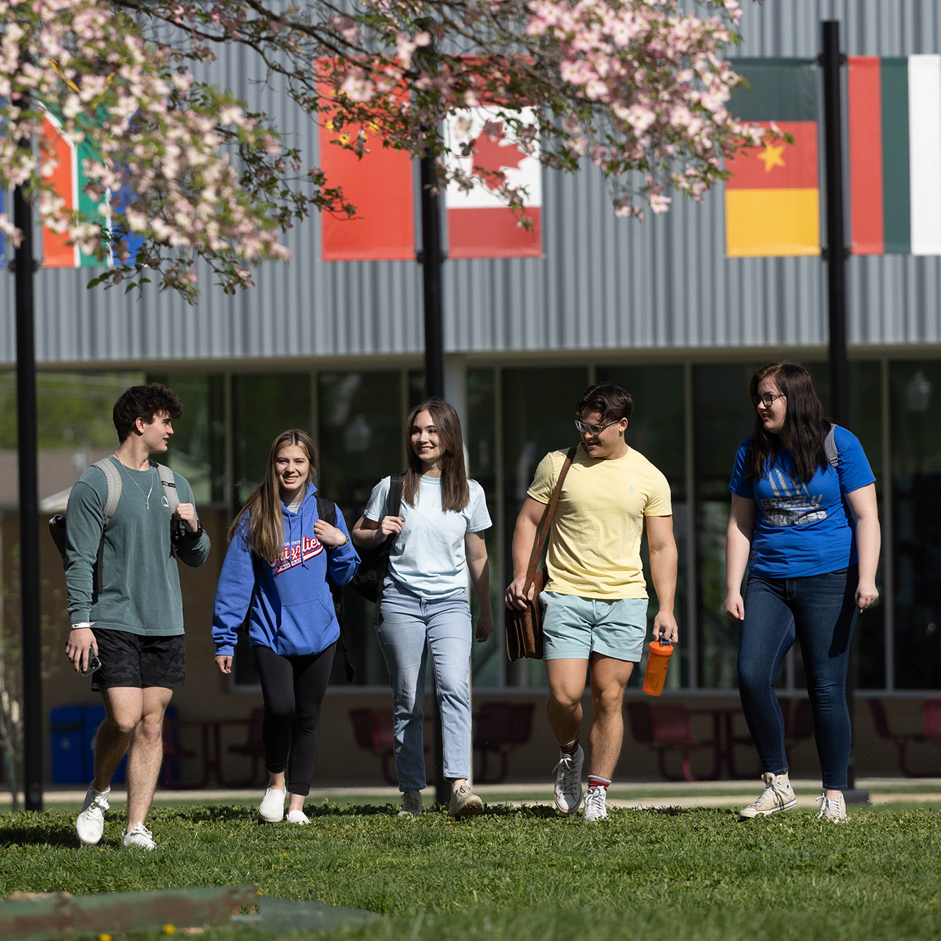 Students walking on campus with flags in the background