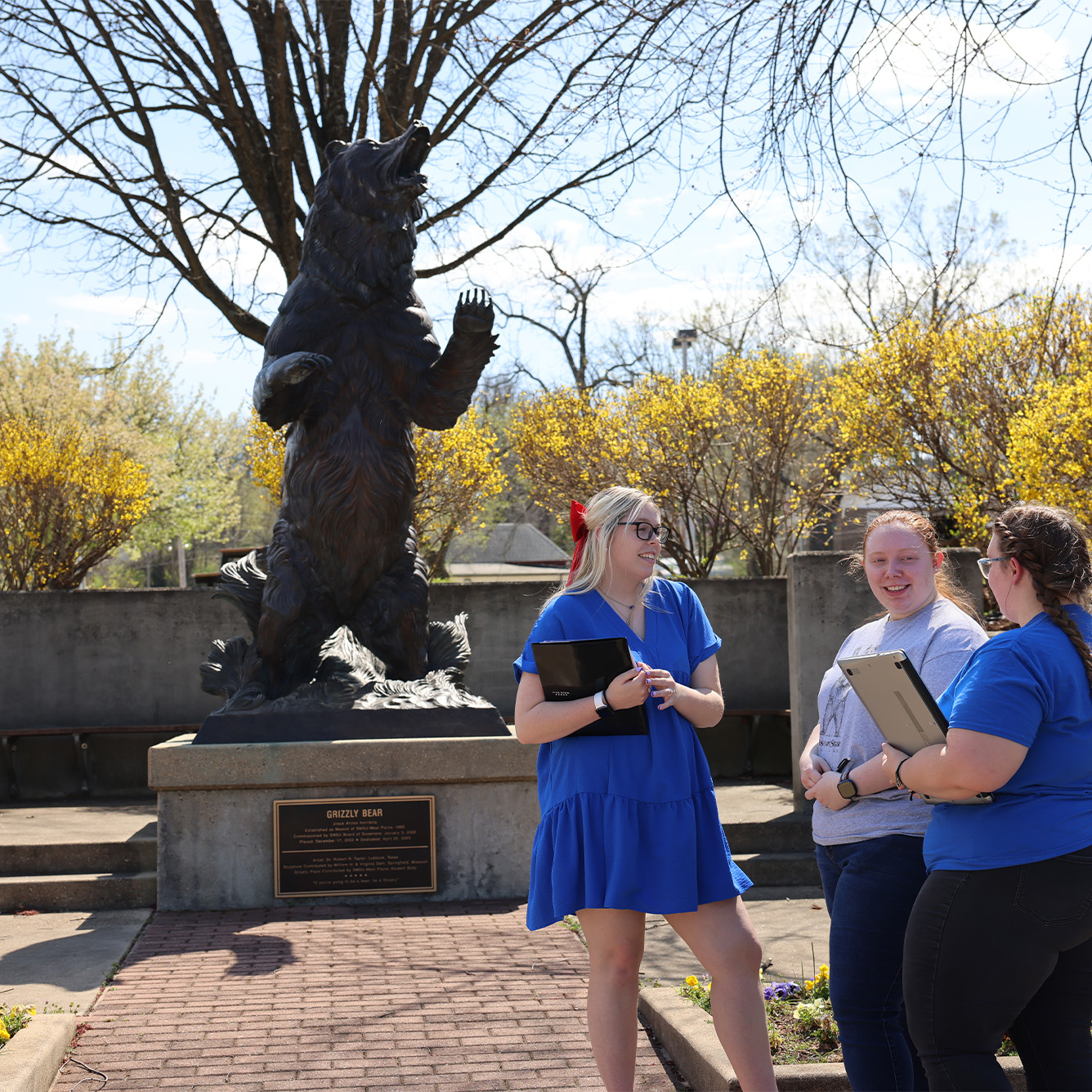 Students on a tour with the Grizzly statue in the background