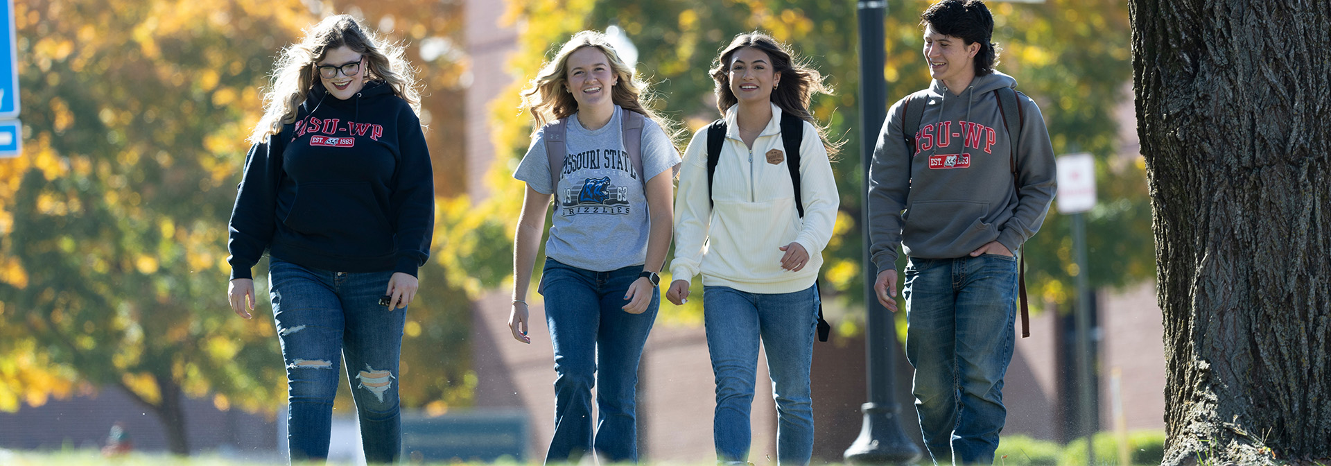 four students walking on campus in the fall